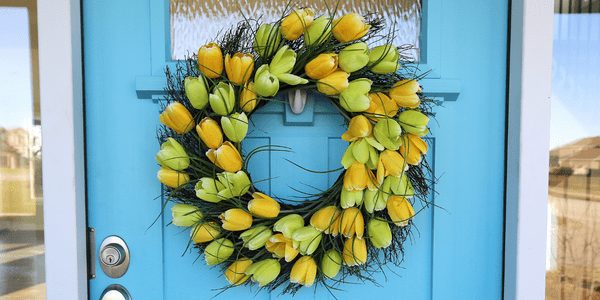 Wreath of yellow tulips hung on bright blue front door